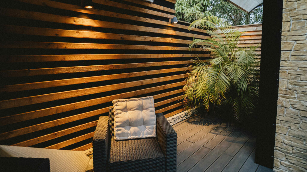 Fauteuil rotin sur la terrasse avec mur de bois ajouré