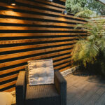 Fauteuil rotin sur la terrasse avec mur de bois ajouré