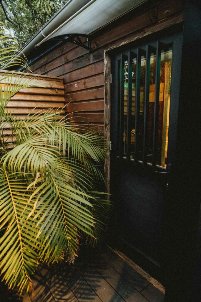 Entrée du lodge en bois entourée de plantes